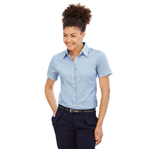 Chemise femme personnalisée brodée bleu ciel portée avec un pantalon noire par une femme brune cheveux relevés.